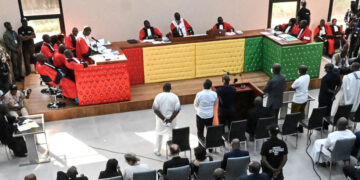 The eleven accused stand as the session starts inside the new courthouse in Conakry on September 28, 2022 during the opening of the trial for the massacre of 156 people in September 2009. - The trial of former Guinean dictator Moussa Dadis Camara and other former officials over the September 28, 2009 stadium massacre opened on September 28, 2022, in the capital Conakry, an AFP correspondent reported. (Photo by CELLOU BINANI / AFP)